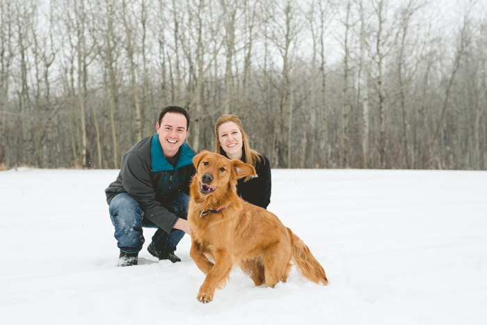 photo of couple with their golden retriever dog in the winter