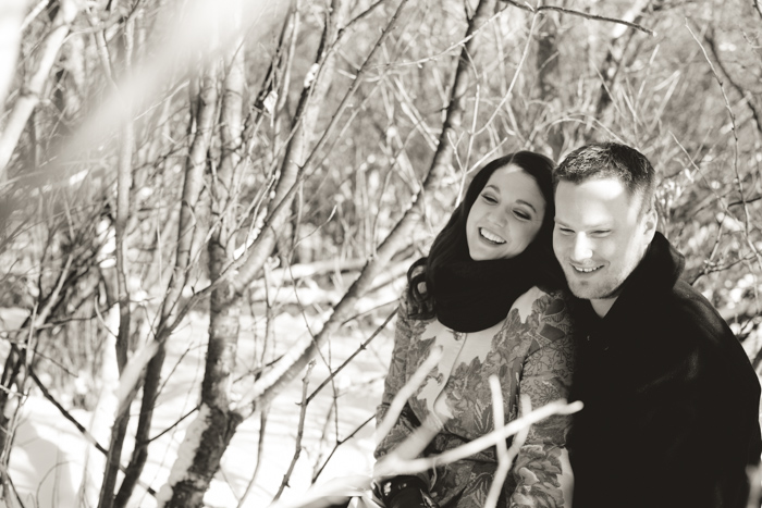 photo of couple sitting in the wintry woods laughing