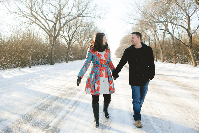 photo of engaged couple walking down a snow covered road