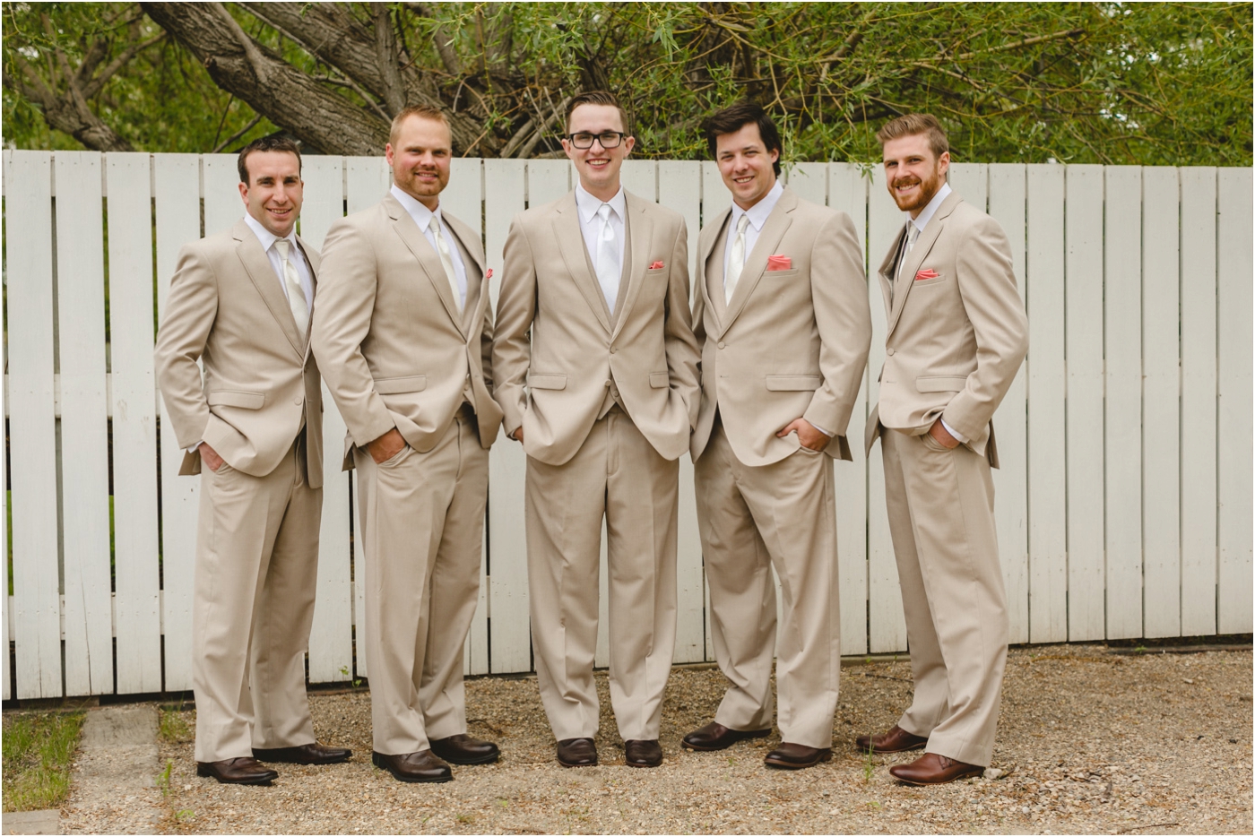groomsmen in matching tan suits with a pop of coral