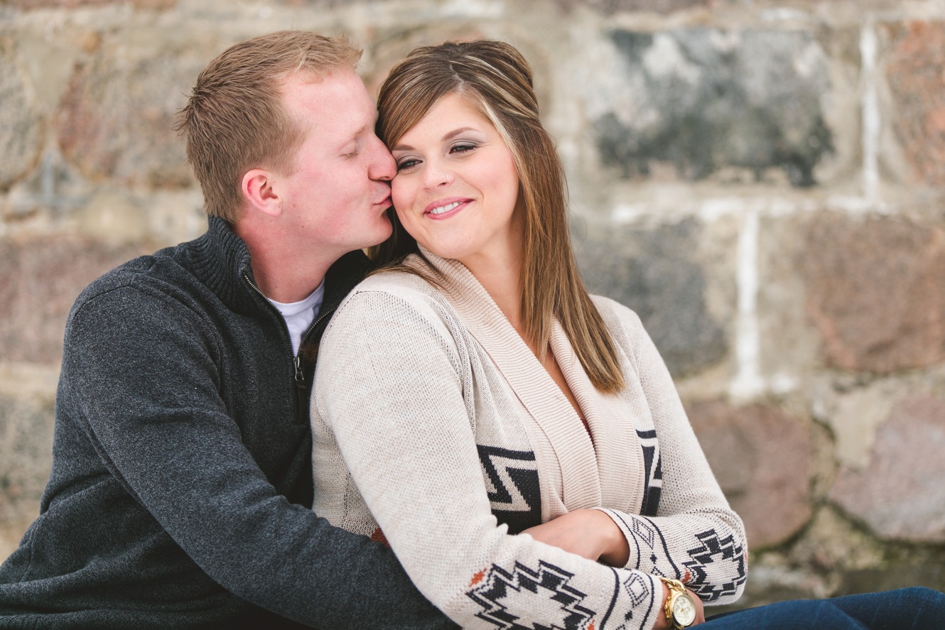 photo of engaged couple on plaid blanket kissing winter engagement photo