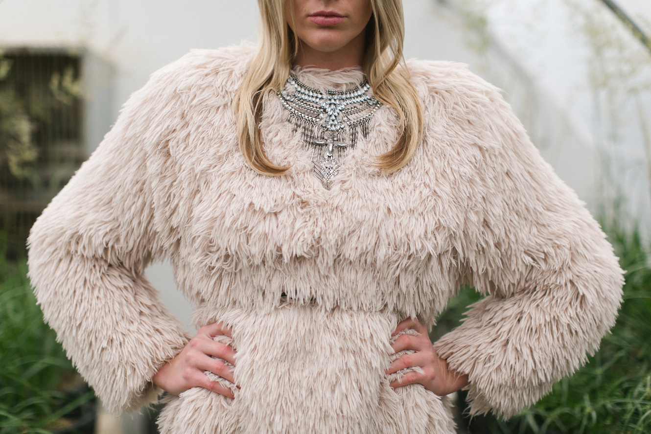 spring greenhouse fashion photo shoot model wearing statement necklace and coat