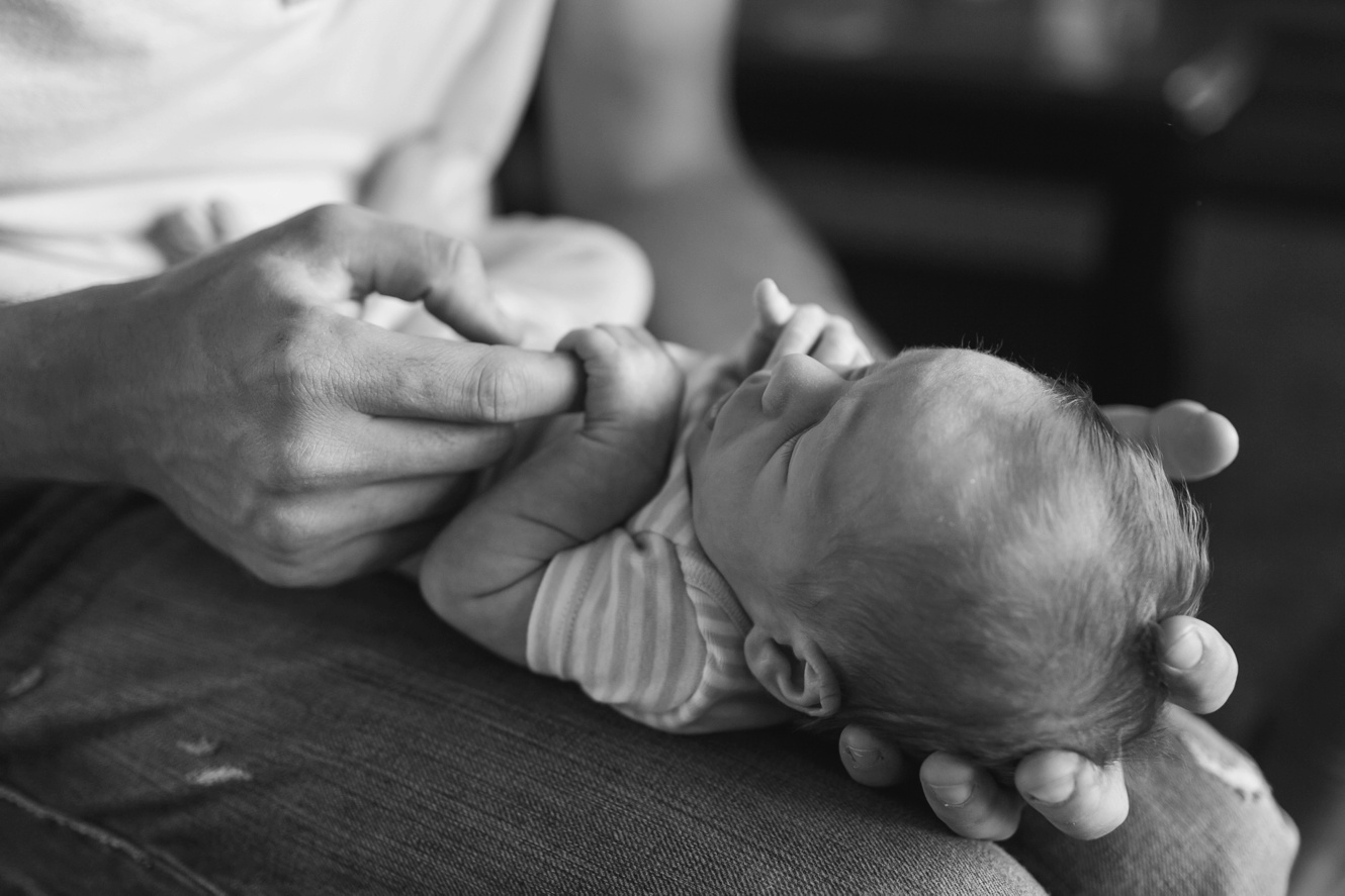 black and white photo of baby holding dad's hand