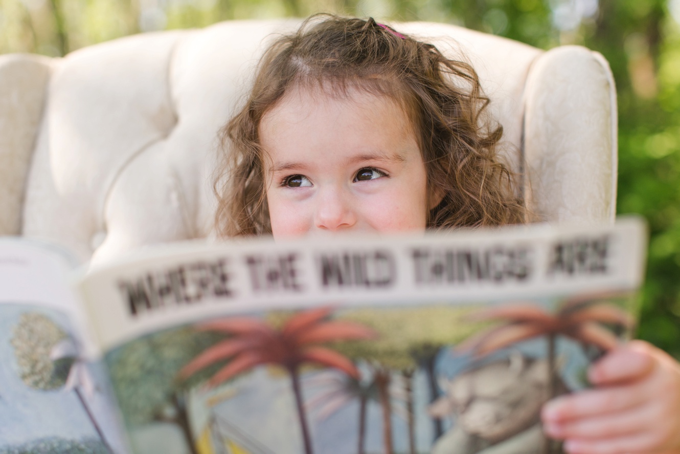 Adorable little girl reading where the wild things are book photo