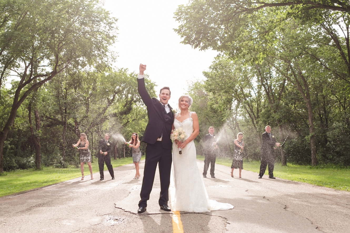 bridal party celebrating with popping champagne at wedding photo