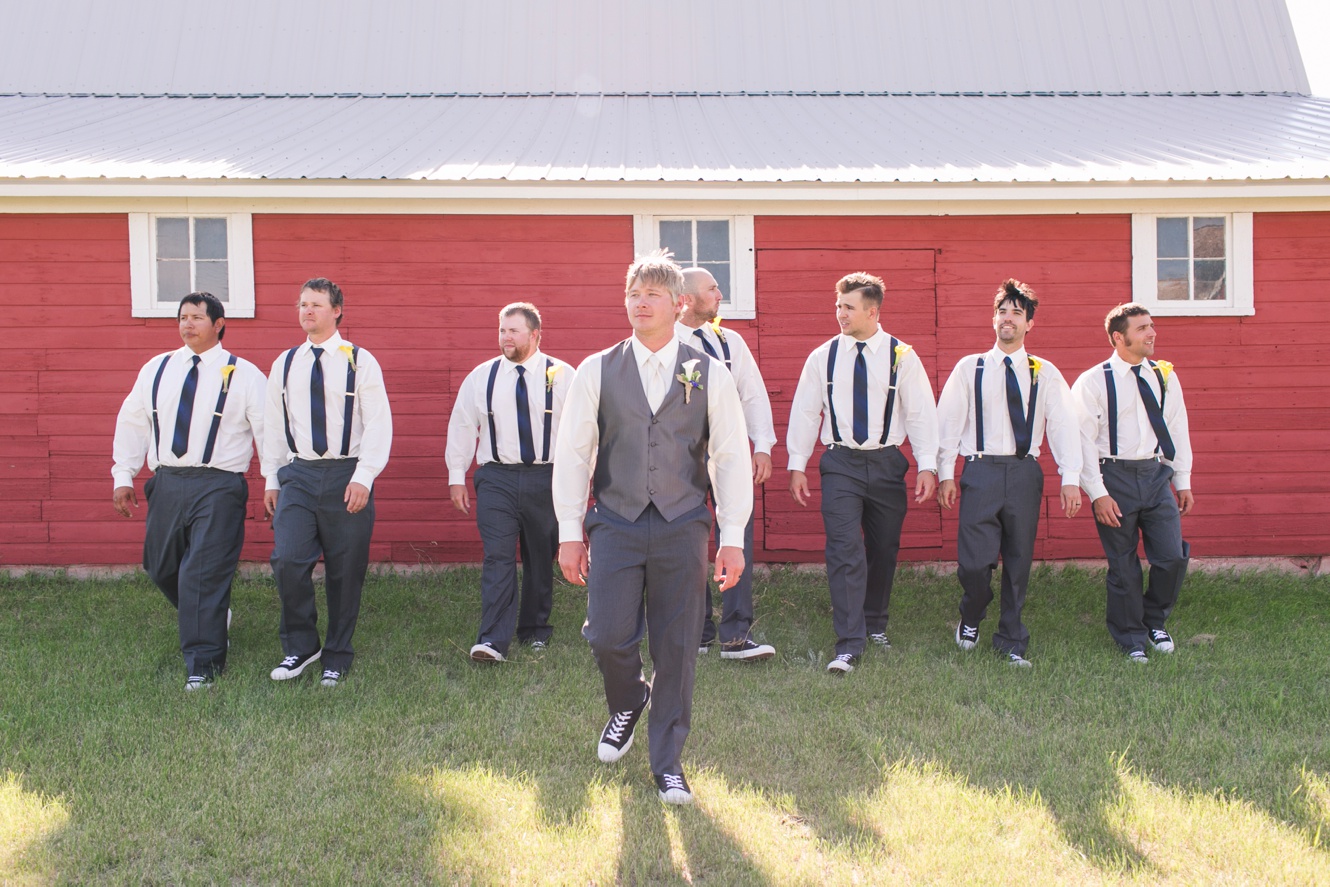 groomsmen posed by a red barn