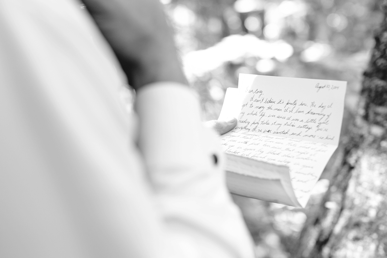 bride and groom exchange letters in the woods on wedding day.