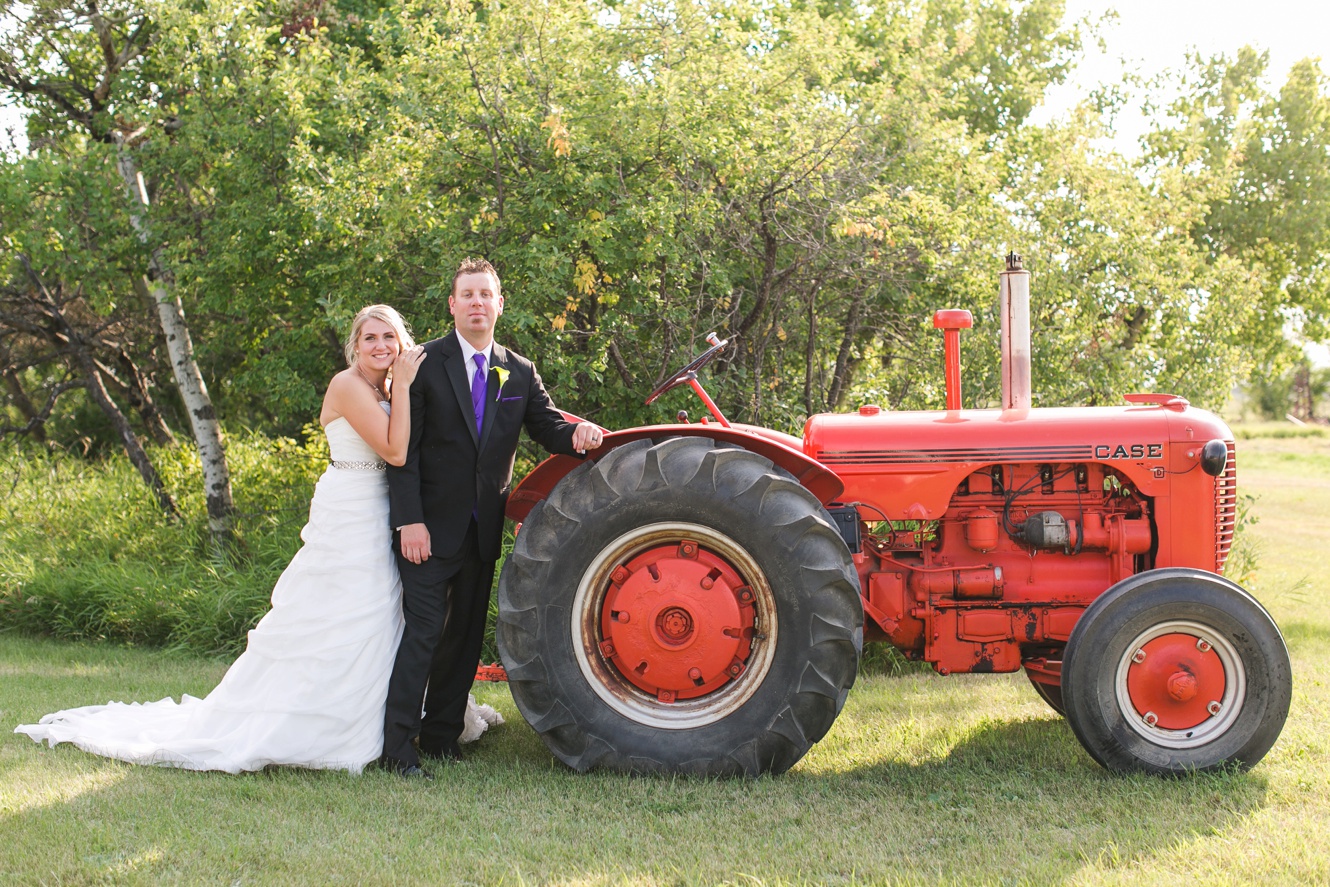 bride and groom pose with old farm tractor