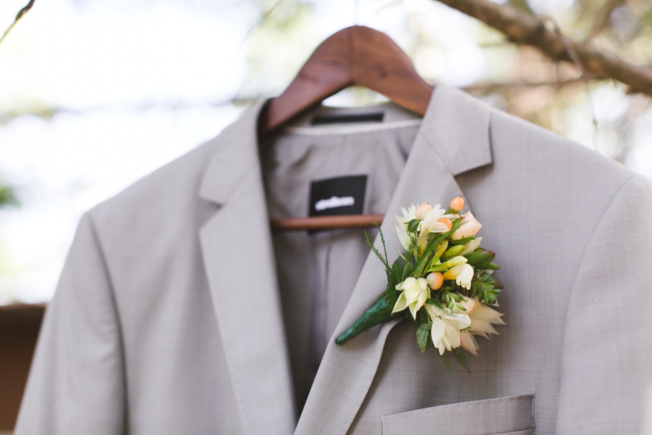 grooms grey suit hanging in a tree photo, unique boutonniere orange and white 