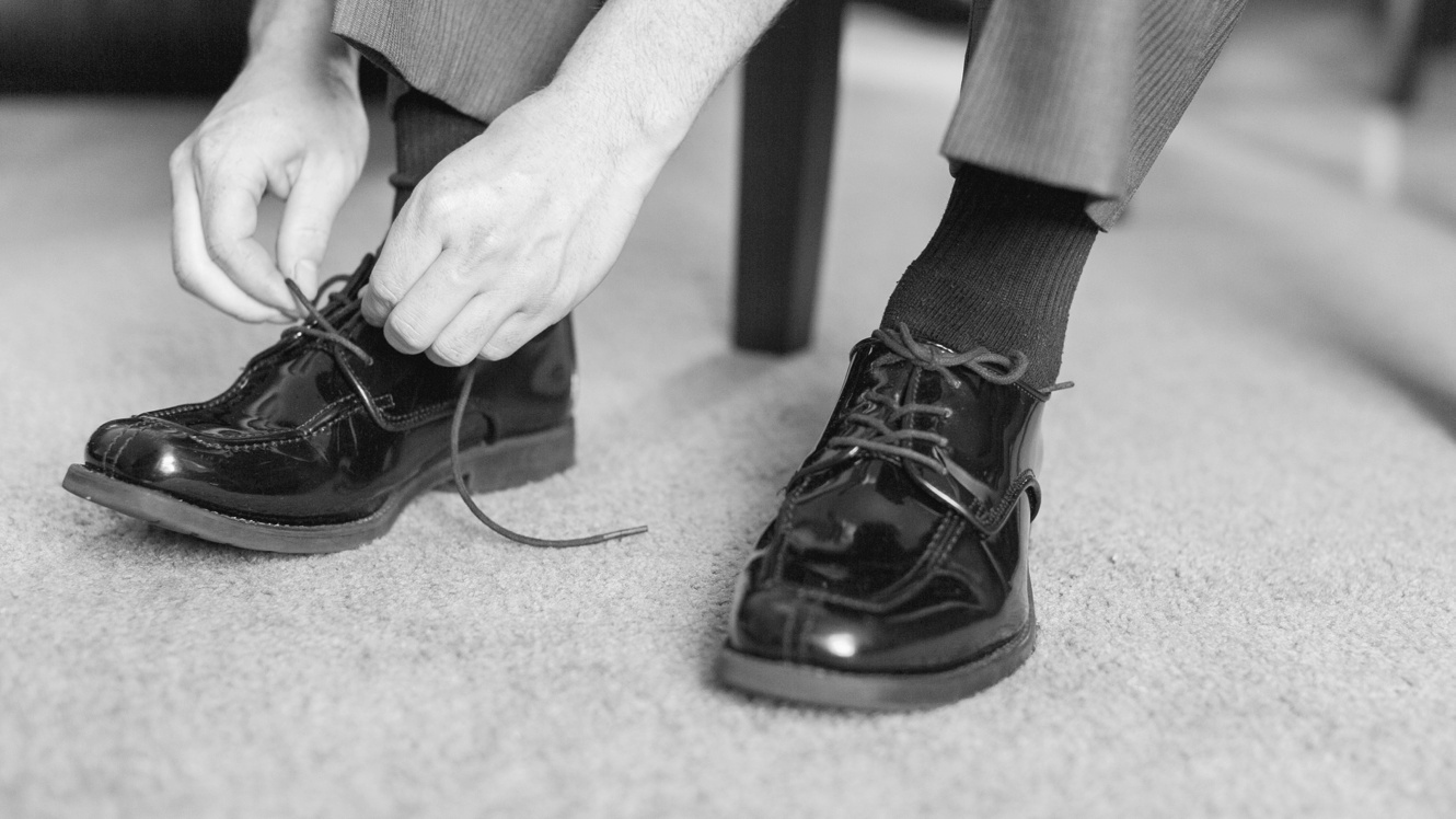 Groom tying shoes black and white