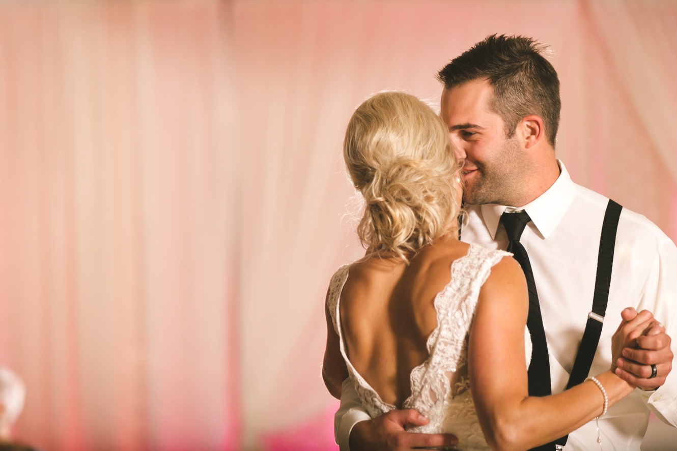 He whispers in her ear during their first wedding dance photo
