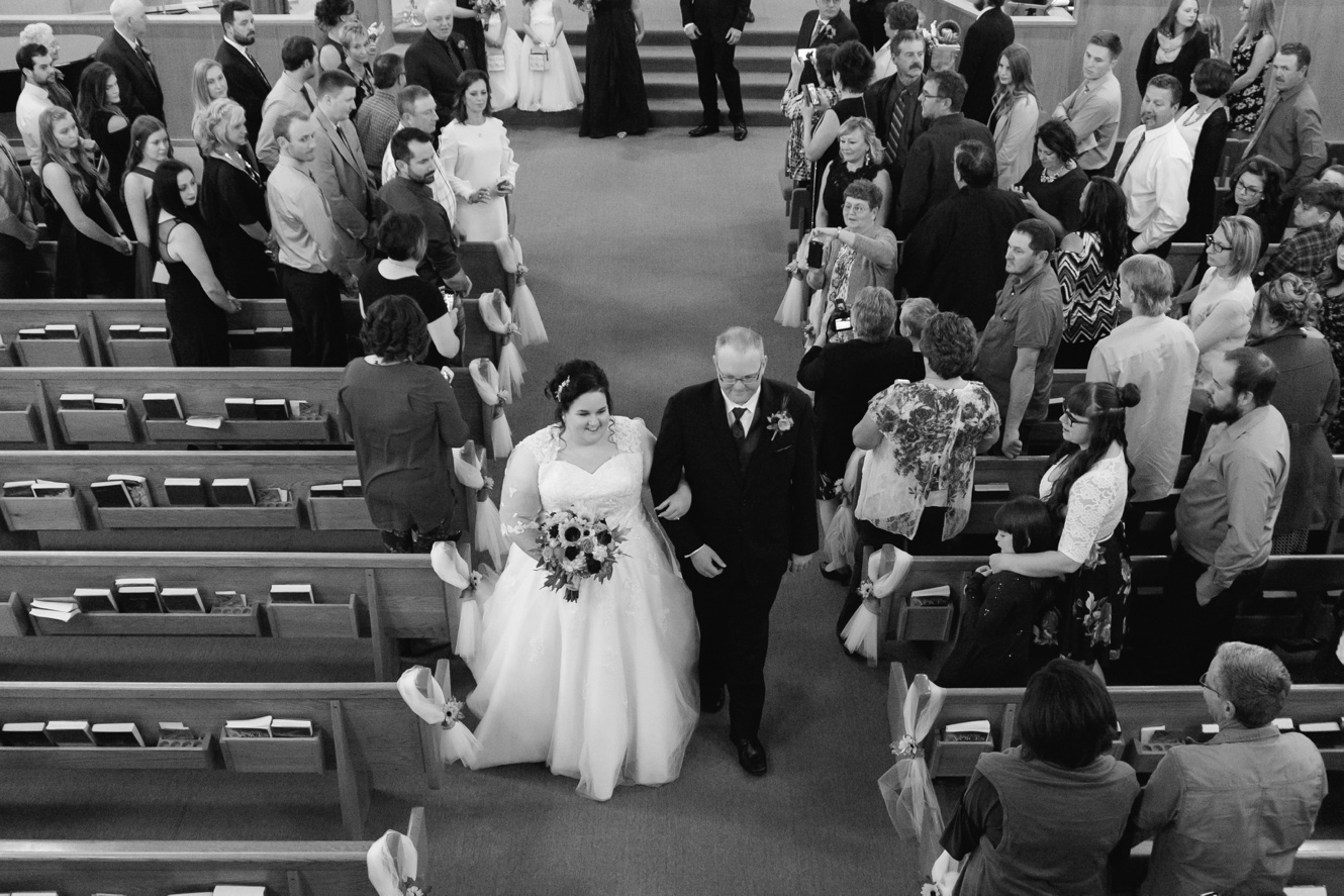 Black and white photo of bride and groom leaving church